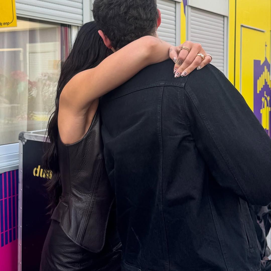 Dua lipa hugging a man with her daisy nails on show 