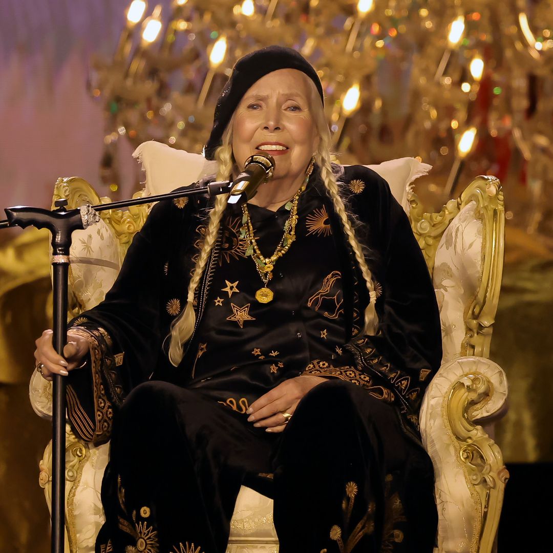 Joni Mitchell speaking on a microphone sitting down