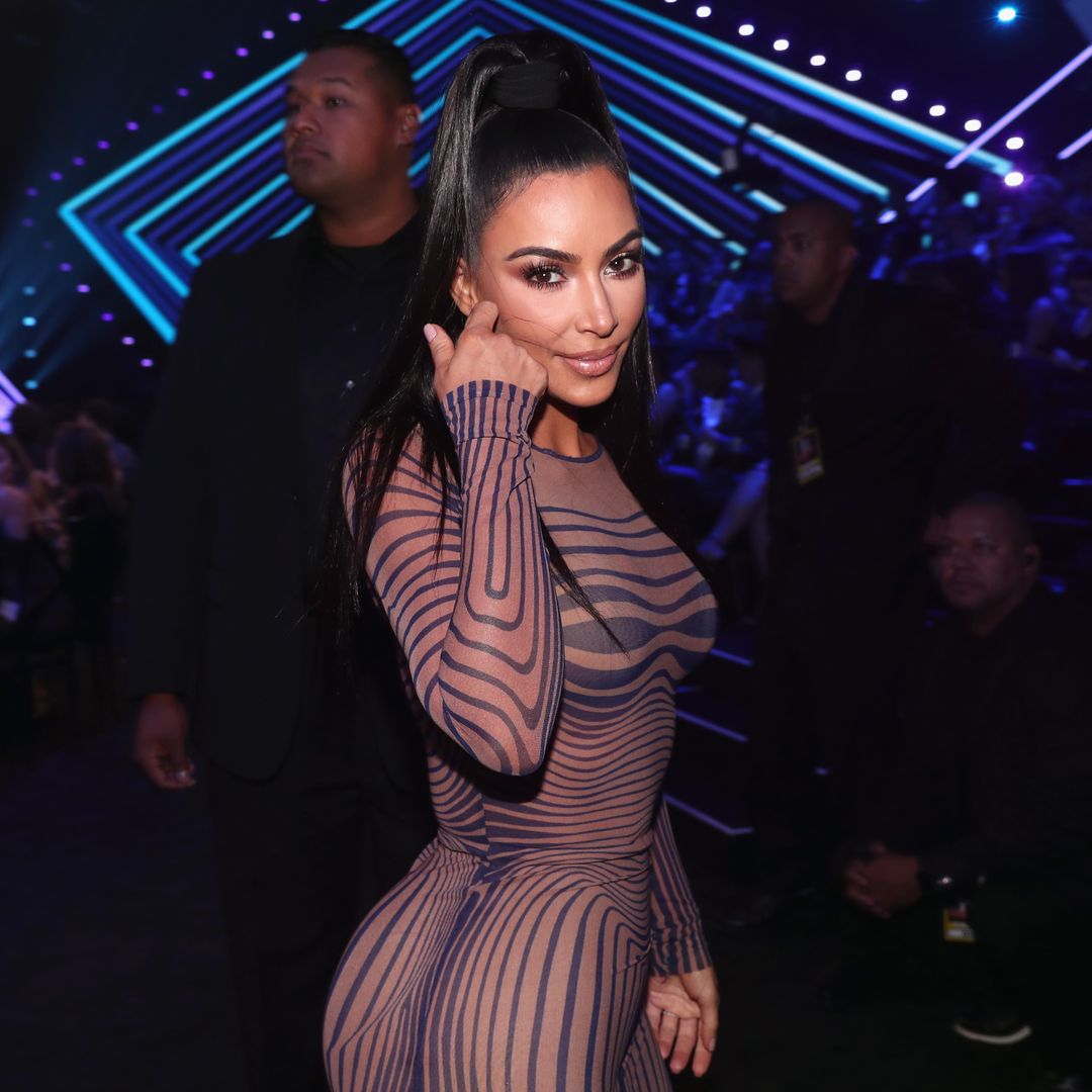 Kim Kardashian smiling at the camera while turning towards it and flicking her hair
