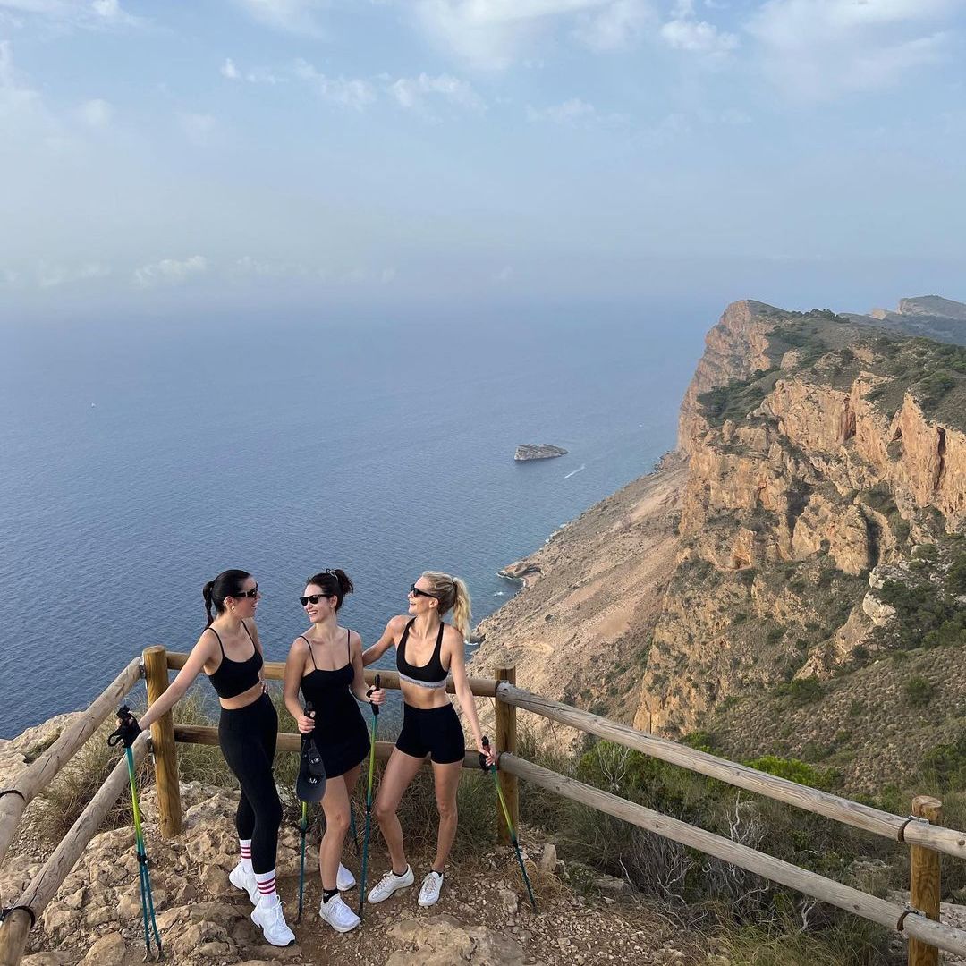 Lily James and her friends hiking at the top of a cliff 