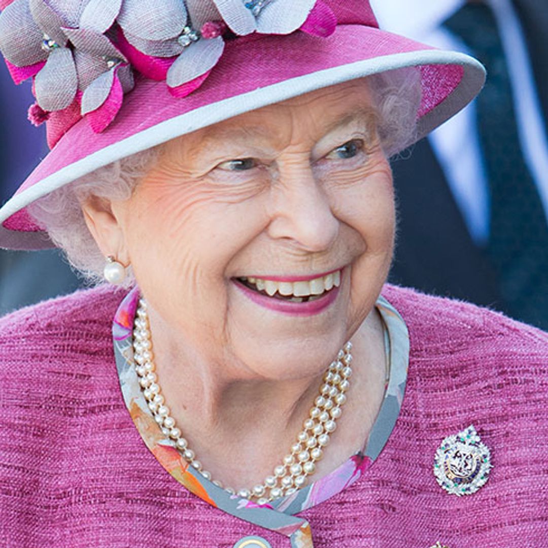 The Queen looks sensational in a colourful floral print dress and pink coat in Scotland