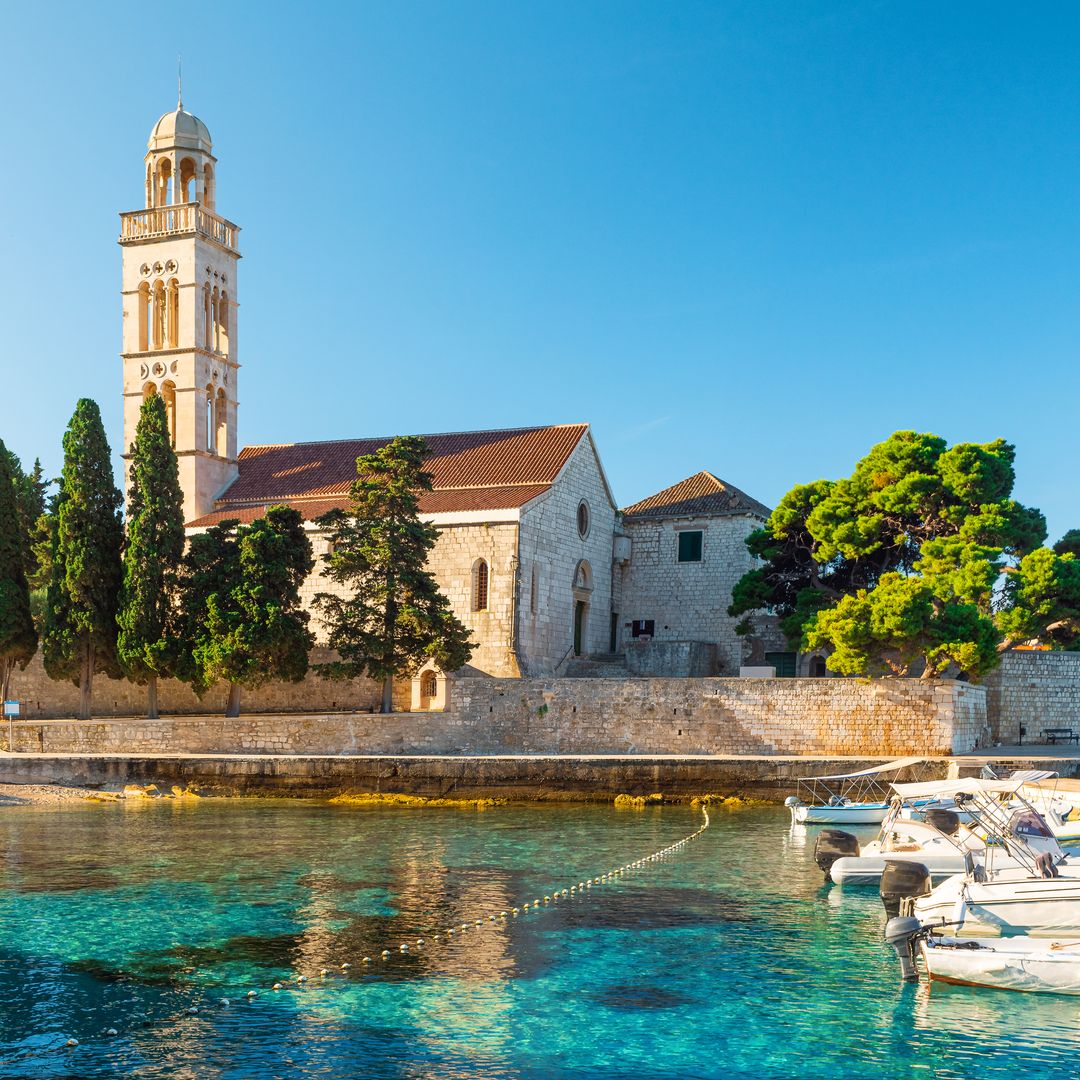 Turquoise water of Adriatic sea bay on Hvar island with franciscian monastery and boats in Dalmatia region, Croatia at sunrise