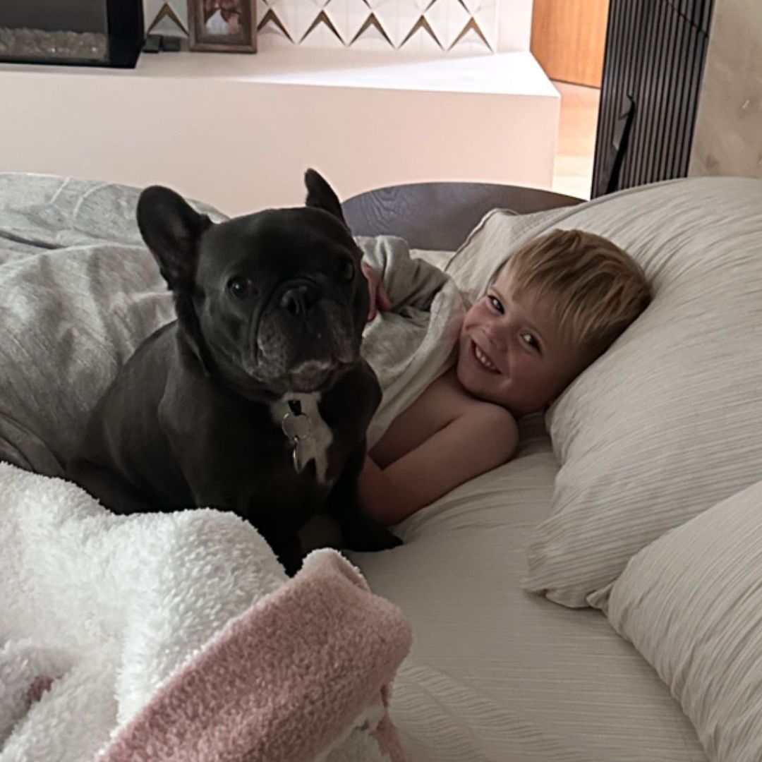 Hudson smiling in bed with french bulldog Cash sat beside him