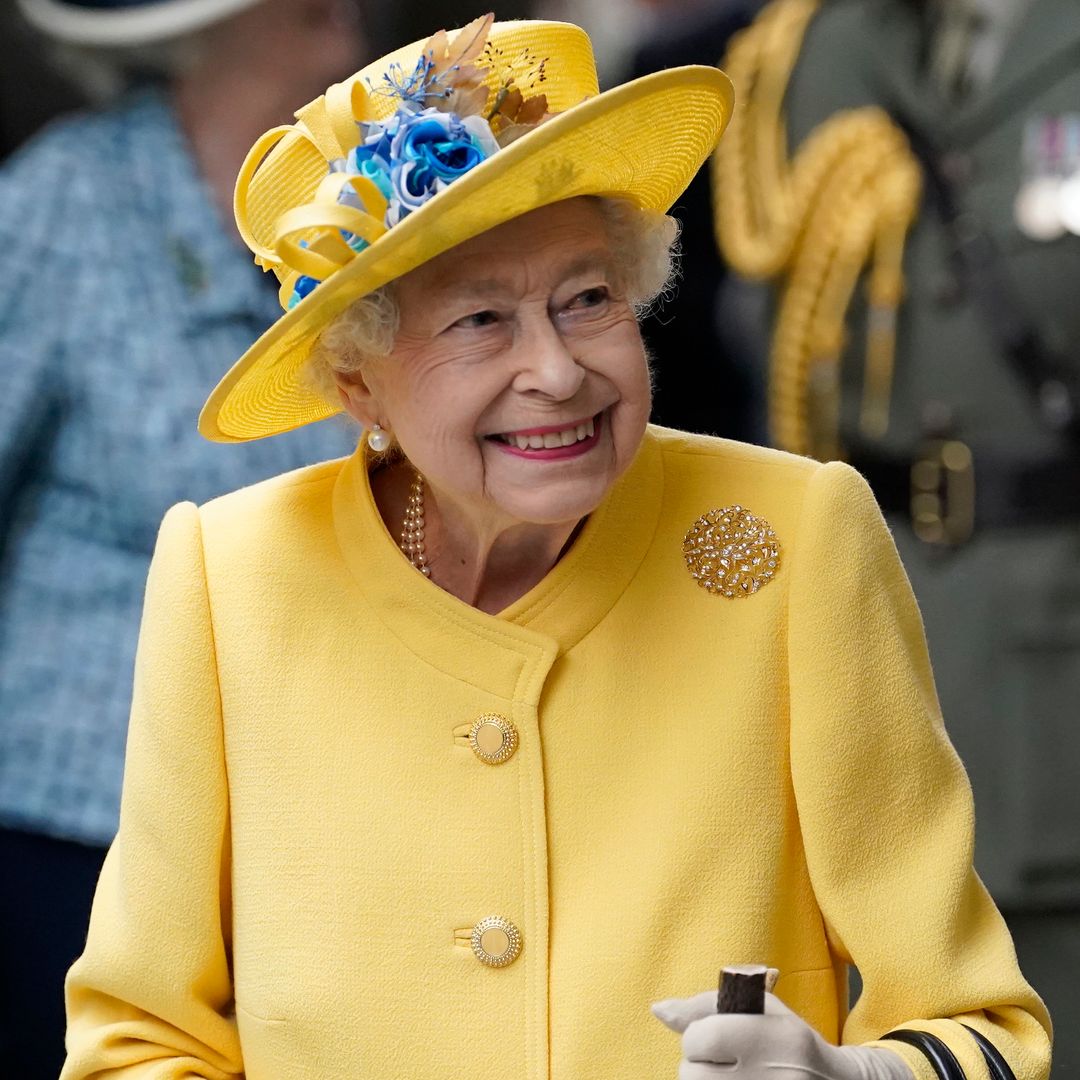 Queen Elizabeth II smiling in a yellow coat and hat