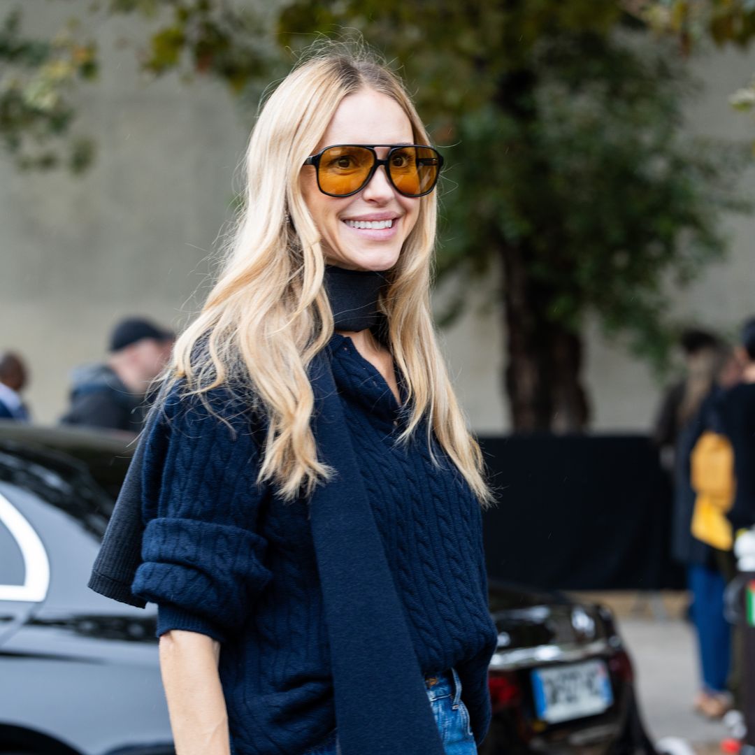 A guest wears a blue scarf, a blue v-neck sweater, high waist blue wide leg jeans and black sunglasses outside ChloÃ© show during Womenswear Spring/Summer 2025 as part of  Paris Fashion Week on September 26, 2024 in Paris, France