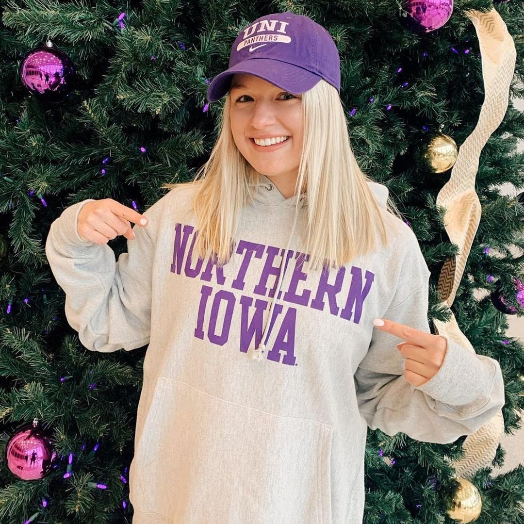 Jenna smiling pointing at her northern iowa sweater