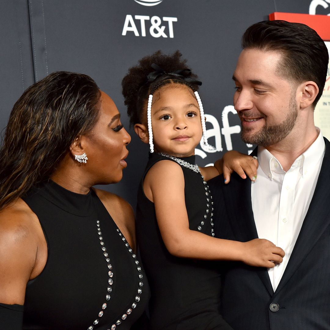 Proud parents Serena and Alexis with their daughter at a red carpet event, Alexis is holding Olympia in his arms