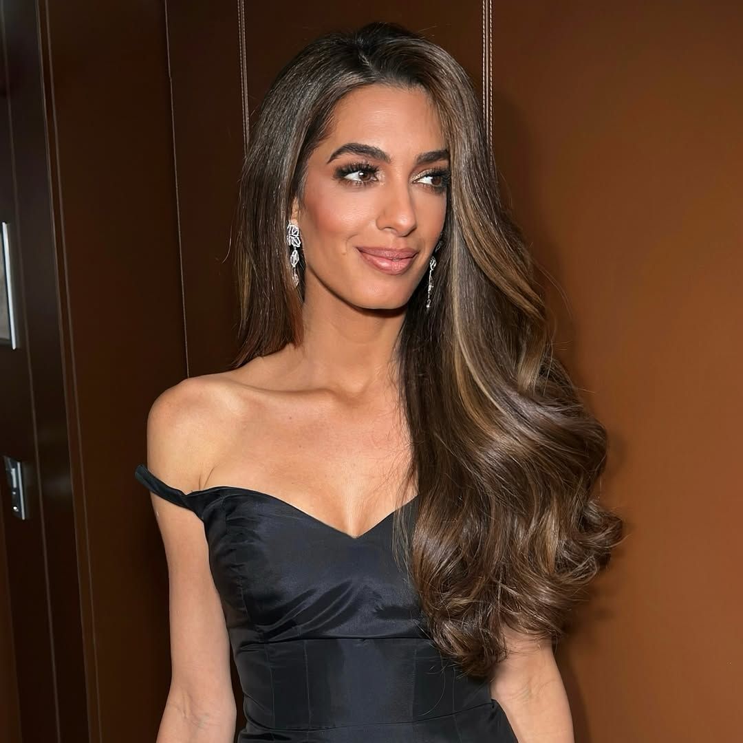 Amal Clooney at cannes wearing a black off the shoulder dress with long chestnut hair
