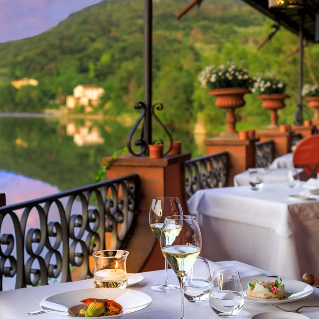 Shot of table with glasses of wine and plates in front of picturesque mountains