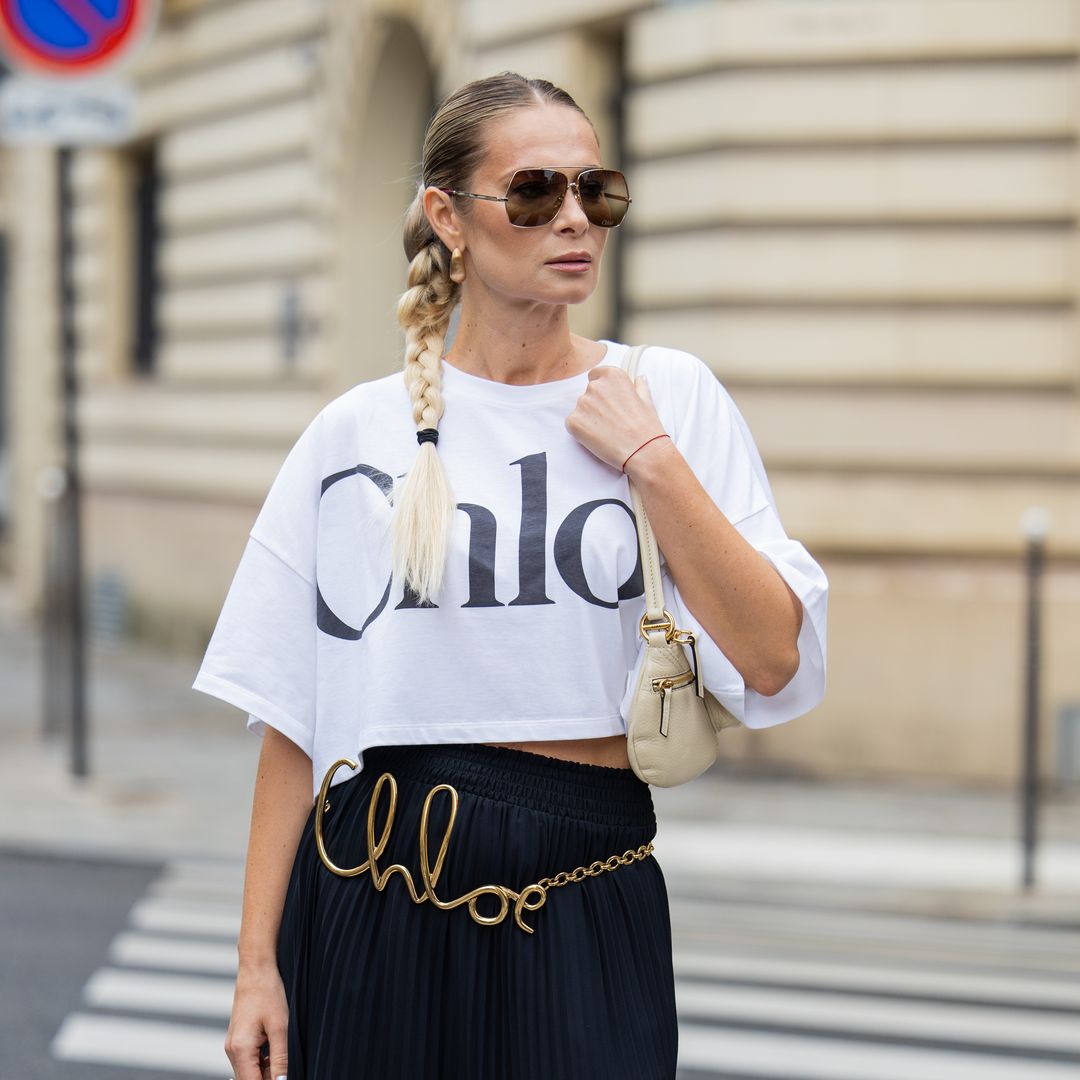 Iryna Thater wears full look Chloe, white shirt with logo, bag, belt with logo, pleated skirt, black over knees boots, sunglasses during Womenswear Spring/Summer 2025 as part of  Paris Fashion Week on September 26, 2024 in Paris, France.