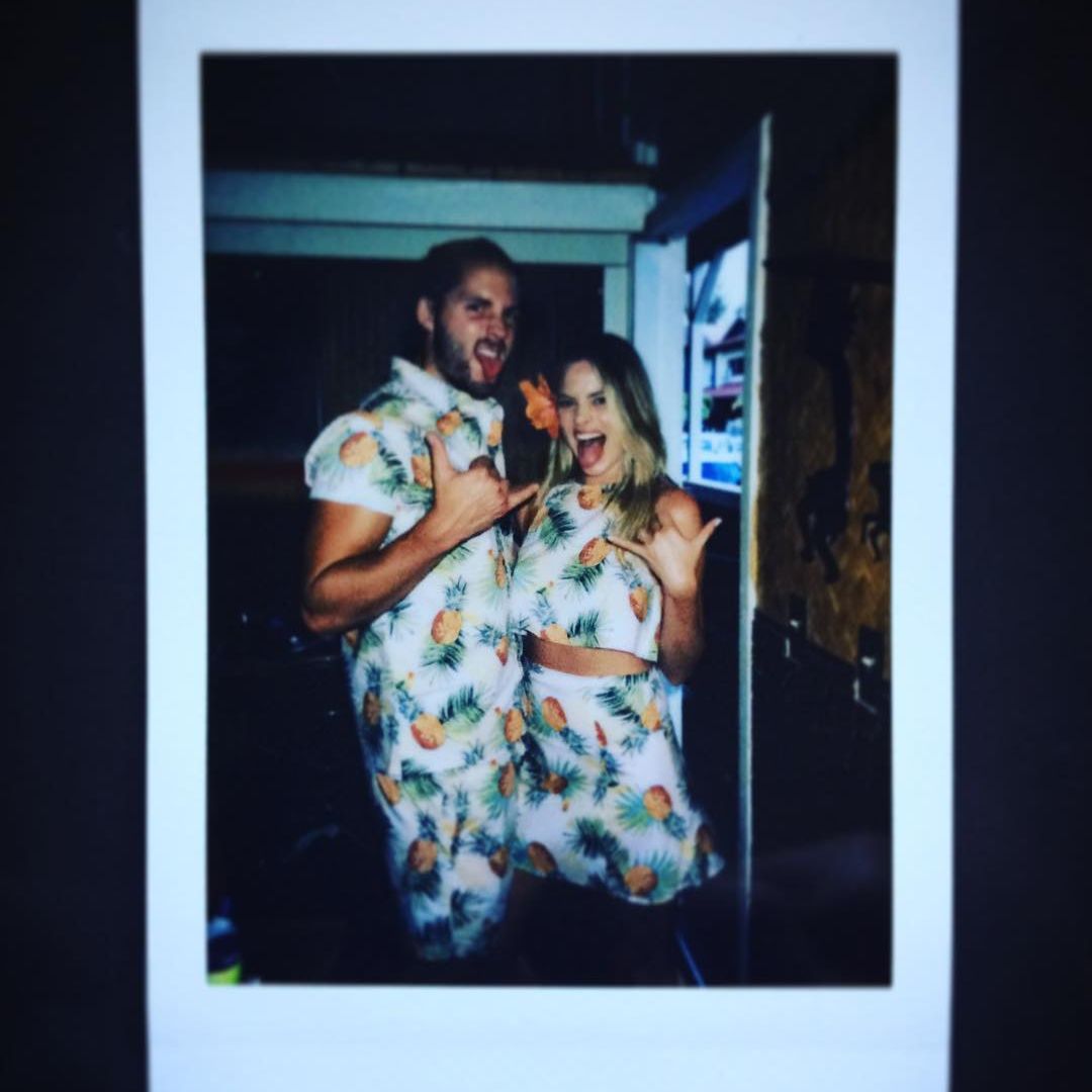 Margot and Tom posing for a photo in matching pineapple print summer outfits