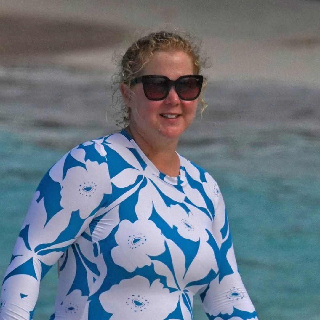 Amy Schumer takes on the beach in an eye-catching swimsuit alongside her husband