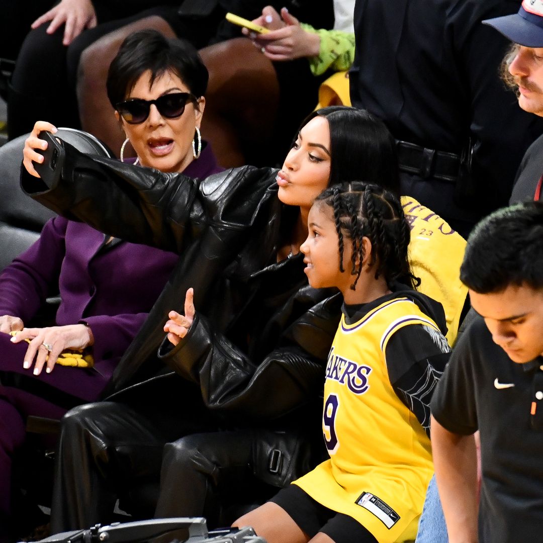 Kim with her mom Kris Jenner and her child Saint West sat at a basketball game