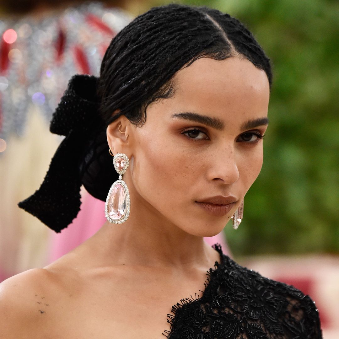 Zoë Kravitz wearing a one-shoulder lace gown with her flock of birds tattoo visible 