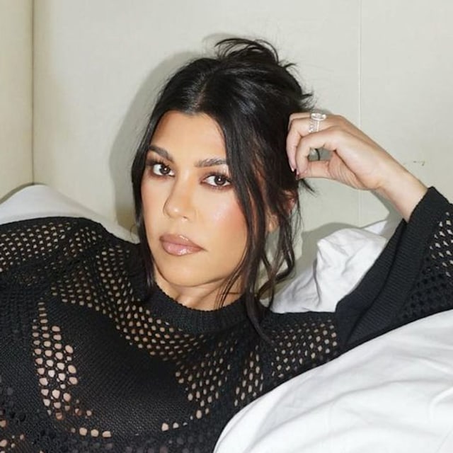 Kourtney Kardashian pregnant relaxing on bed wearing black mesh dress