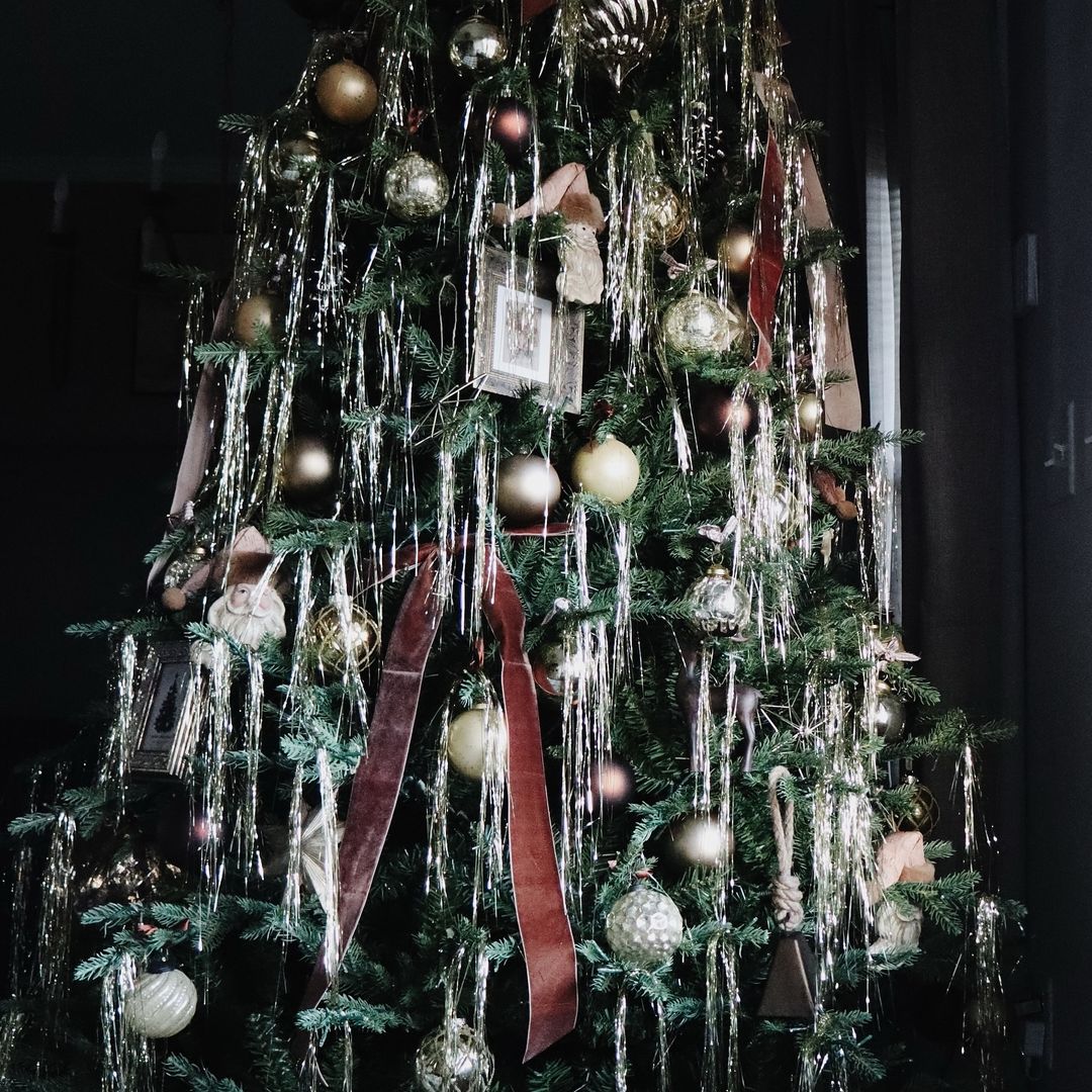 A Christmas tree covered in Angel's Hair and vintage looking baubles. There are also big ribbon bows on the tree in shades of dark pink and peach