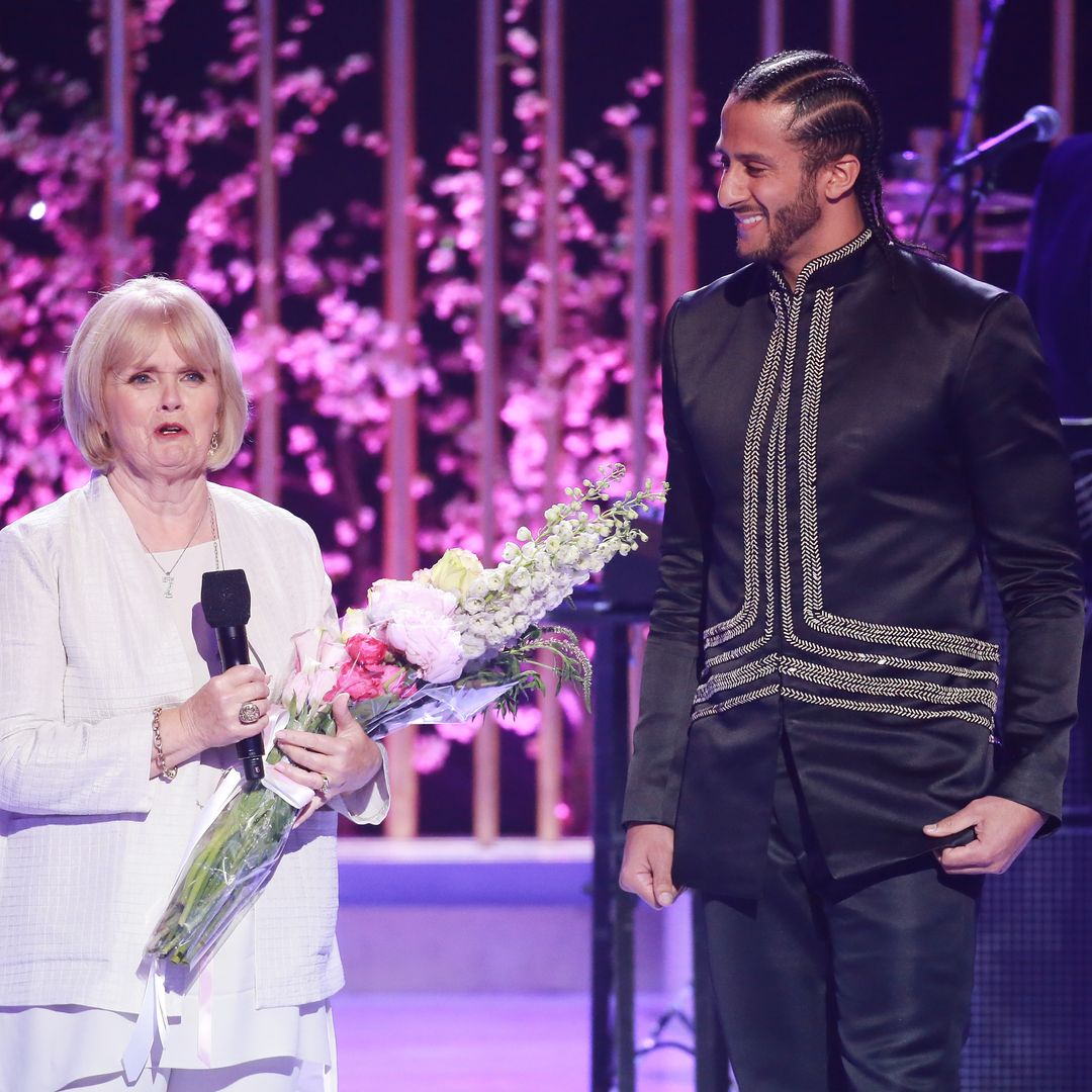 Teresa and Colin smiling on stage, he is looking proudly at her, she is holding a bunch of flowers