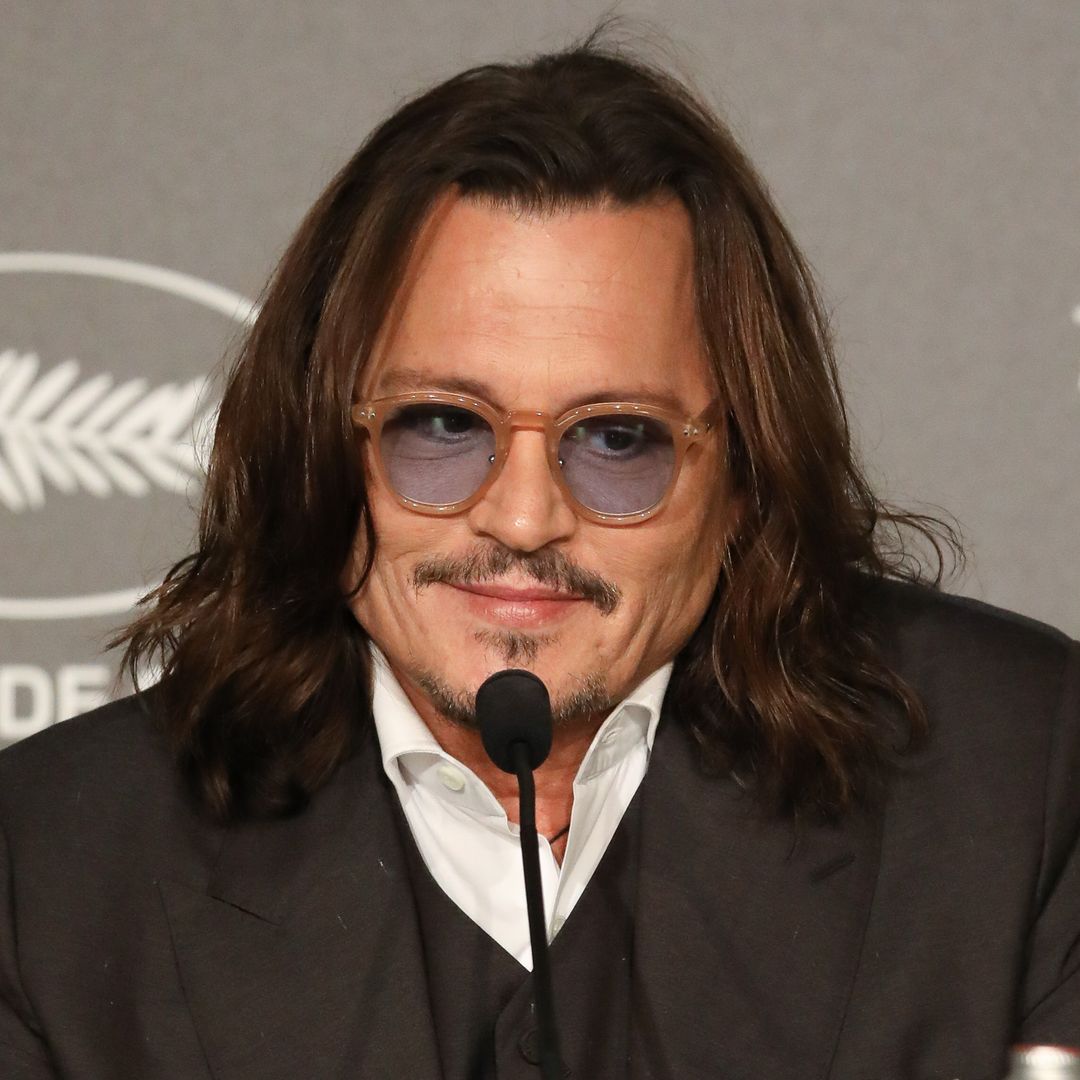 Johnny Depp smiling while sat at a press conference