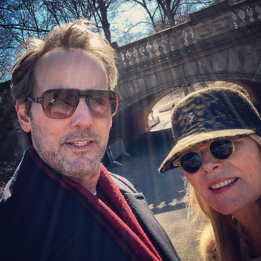 Kim Cattrall and Russell Thomas smiling for a selfie in sunglasses by a bridge in central park
