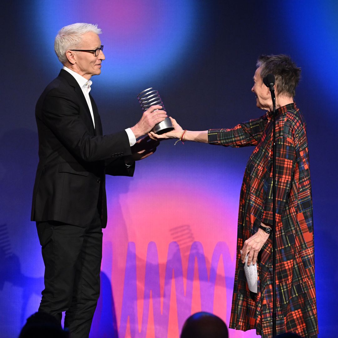 Anderson Cooper receiving a Webby award from Laurie Anderson on stage in May 2023