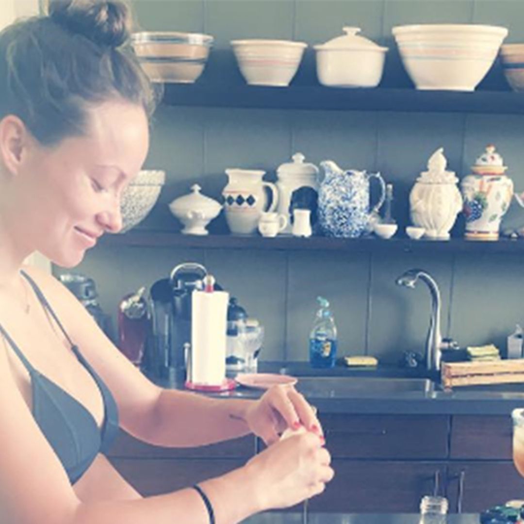 Olivia Wilde shows off her bare baby bump while cooking in a bikini