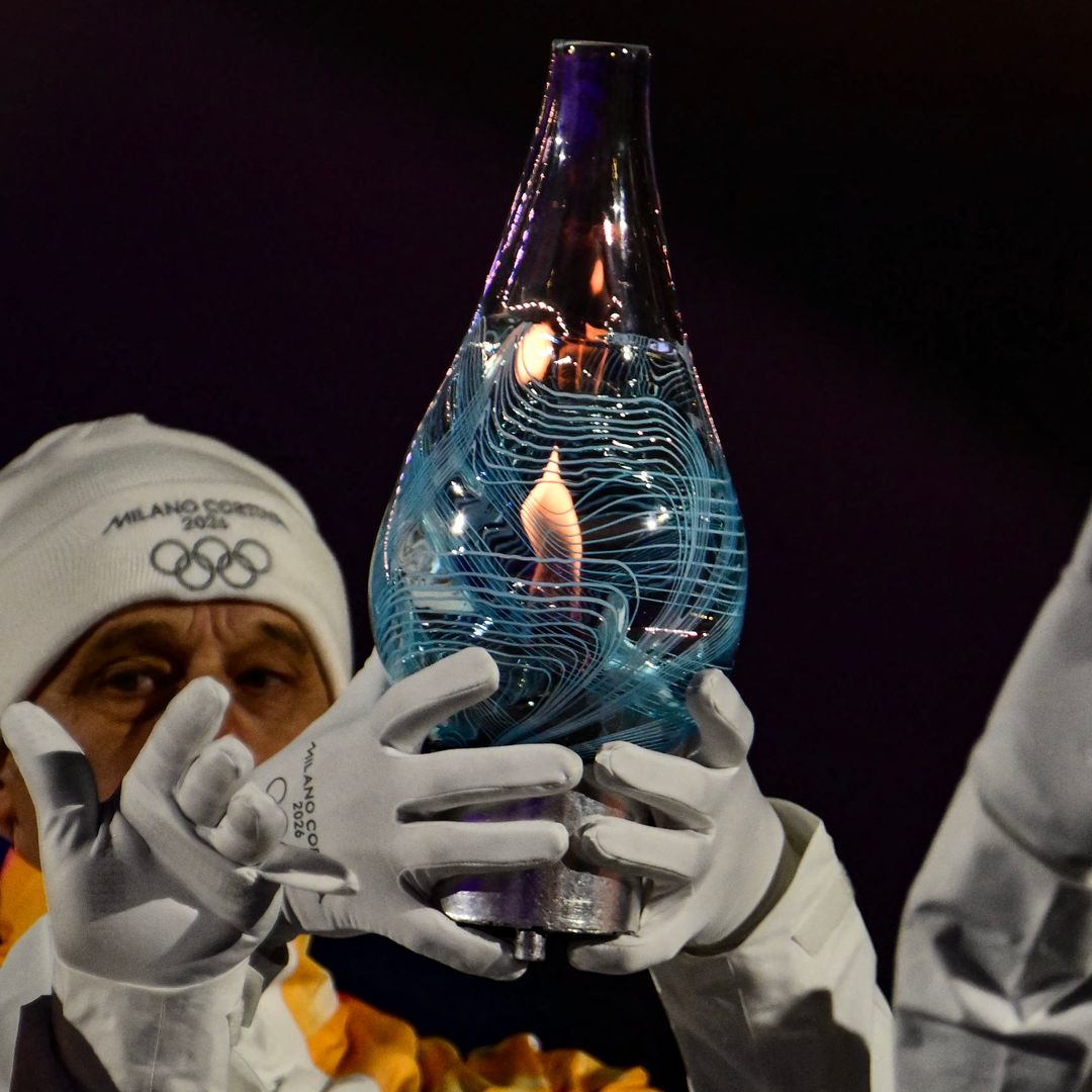 TOPSHOT - L'équipe italienne médaillée d'or du relais de ski de fond de 4 à 10 km des Jeux olympiques d'hiver de 1994 porte la flamme olympique dans le verre de Murano lors de la cérémonie de clôture des Jeux Olympiques d'hiver de Milano Cortina 2026 à l'arène de Vérone, dans le nord de l'Italie, le 22 février 2026.