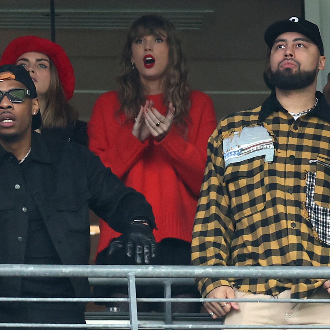 Taylor Swift wearing a red jumper watching the match alongside model Cara Delevingne