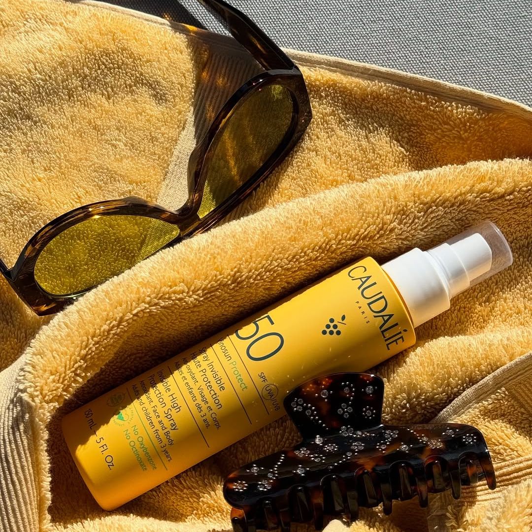 Beach bag essentials - Caudalie suncream, sunglasses and a hair clip