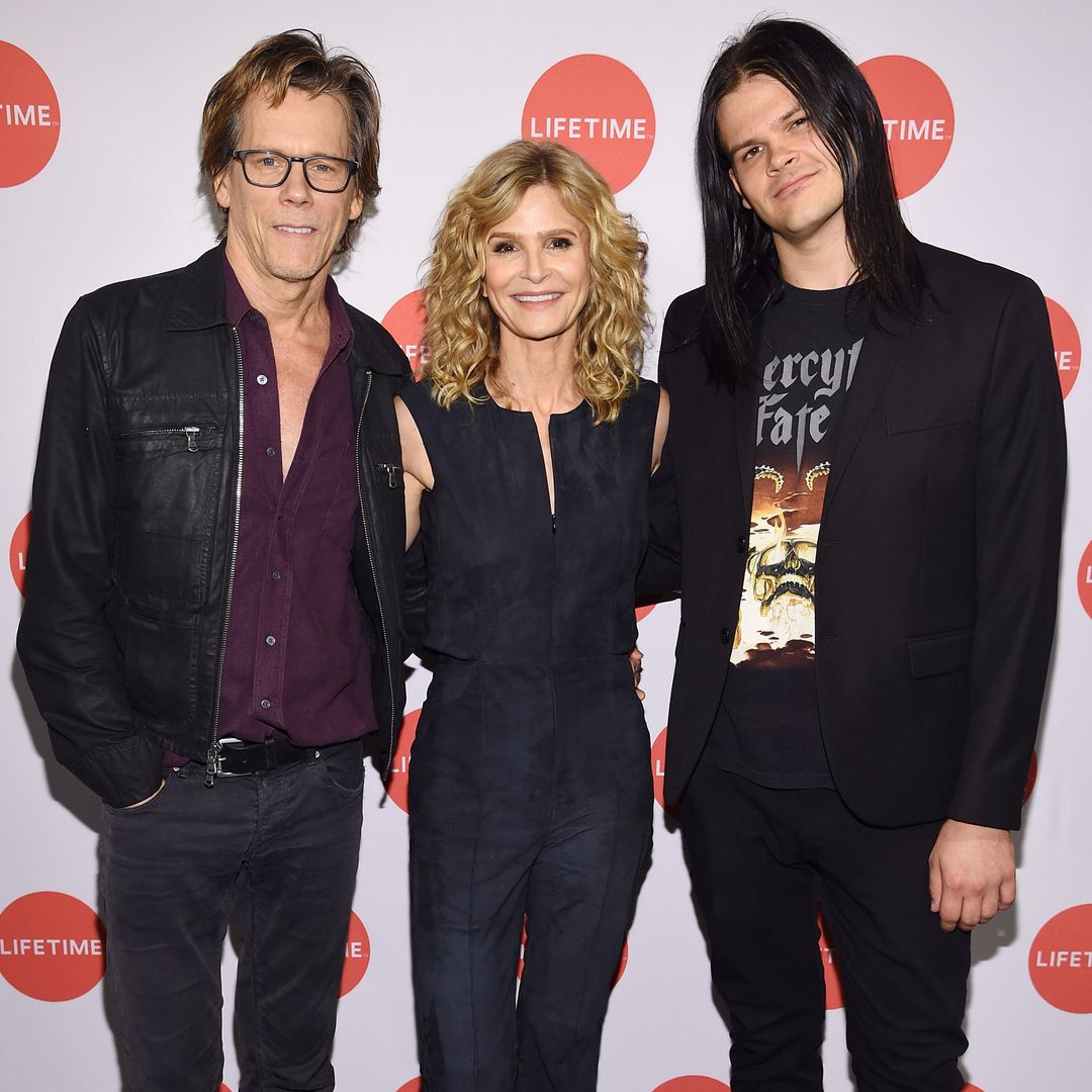 Kyra Sedgwick, Kevin Bacon and their son Travis Bacon smiling on a red carpet