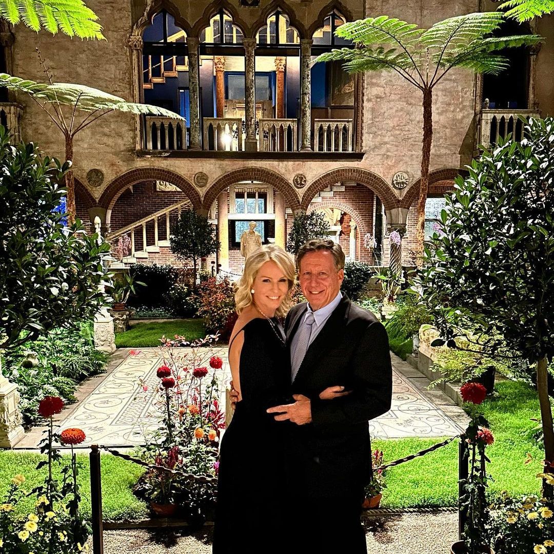 Jennifer and her husband embrace in a villa like garden