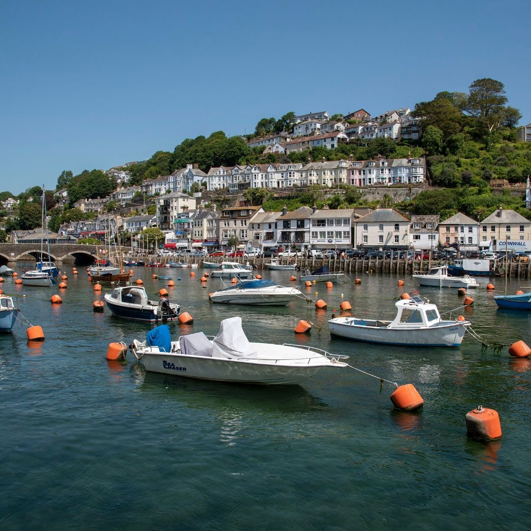 Houses perched on a seafront cliffside and near the water, boats moored in the water in the foreground