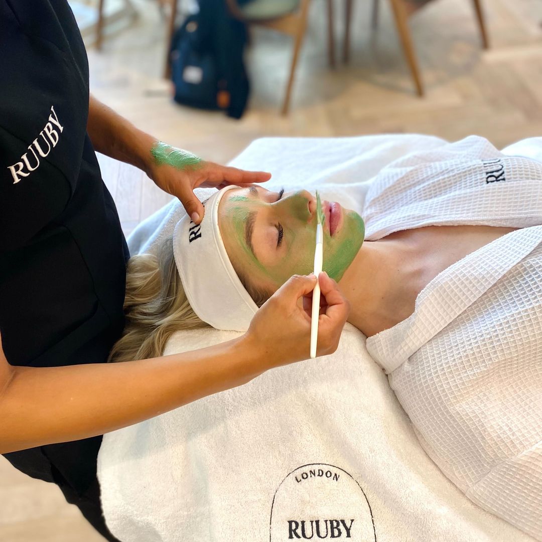 Woman having face mask applied on treatment bed