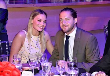 Margot Robbie and Tom Ackerley smiling in a close-up photo.