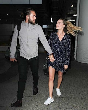 Margot Robbie and Tom Ackerley holding hands.