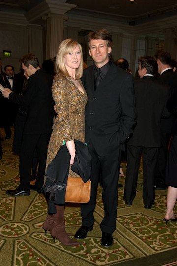 Sarah Lancashire in a yellow dress with her husband Peter dressed in black