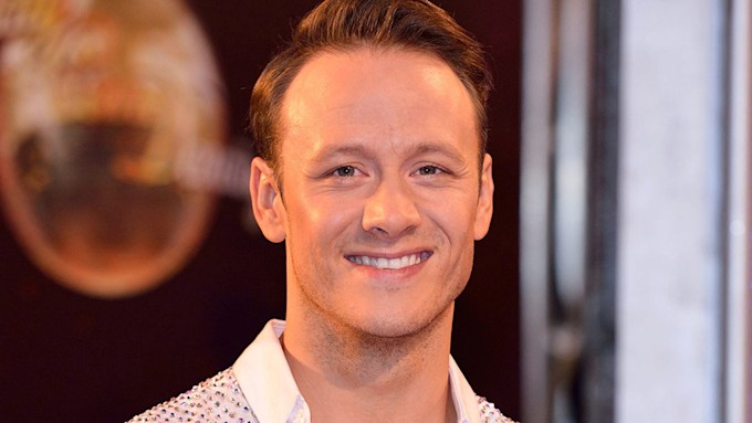 Kevin Clifton smiling in a white jewelled shirt