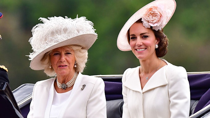 Camilla and Kate smiling in matching white outfits and hats