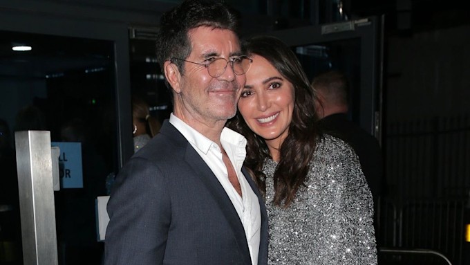 Simon Cowell wearing a suit as he cuddles Lauren Silverman in a sparkly dress