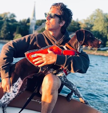 David Muir holds his dog Axel on a boat