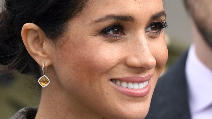 meghan markle up close wearing hair tied back and amber earrings