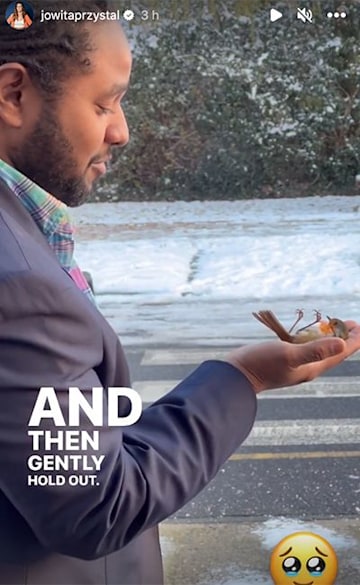 Hamza holding a tiny robin in his hand as he stands outside