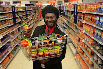 Levi Roots holding a basket filled with his Reggae Reggae sauce. 