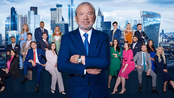 Lord Alan Sugar standing with his arms folded and all season 17 contestants behind him. 
