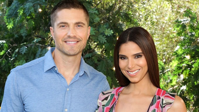 Eric Winter and Roselyn Snachez cuddle up for a photo outdoors.