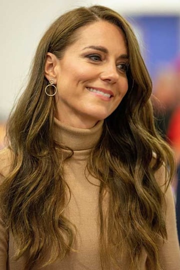 Kate Middleton smiling in a beige turtleneck top 