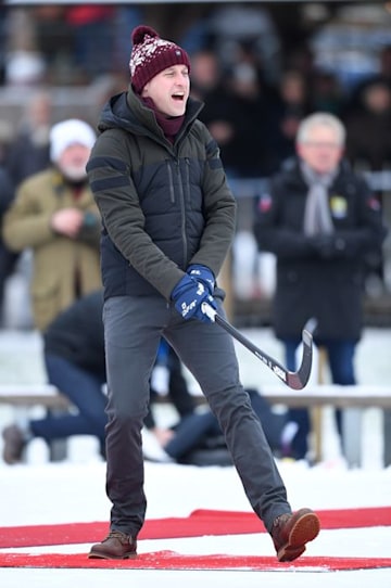 Prince William in winter clothes and cap playing ice hockey in Sweden