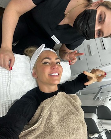Danni Menzies lying on a facialist bed smiling