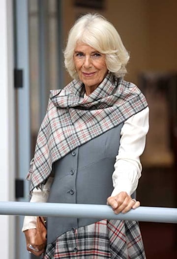Queen Consort Camilla smiling wearing a tartan scarf