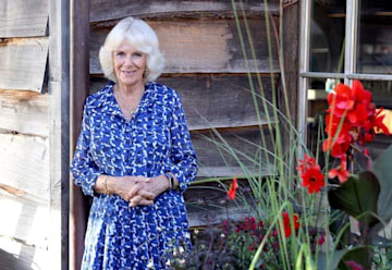 Queen Consort Camilla smiling outside in a blue dress