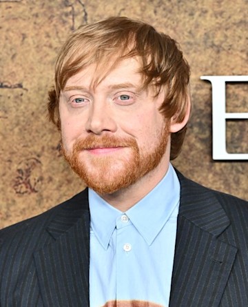 Rupert Grint smiling in a suit